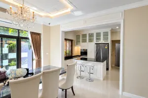 ชุดครัวสีขาวและพื้นที่รับประทานอาหารใต้โคมไฟระย้า