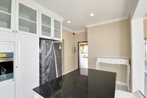 ตู้ครัวสูงและเคาน์เตอร์สีดำในห้องโทนขาว