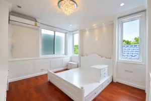 ฐานเตียงสีขาวและหัวเตียงทรงโค้งในห้องนอน มีชุดลิ้นชักเล็กวางบนฐานเตียง