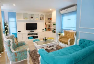 ห้องนั่งเล่นโทนฟ้าพร้อมตู้ทีวีบิ้วอินสีขาวและโซฟาสีเทอร์ควอยซ์ในบ้าน Nirvana Beyond