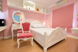 ห้องนอนสีชมพูพร้อมเตียงหัวโค้งและโต๊ะเครื่องแป้งสีขาวสไตล์วินเทจ