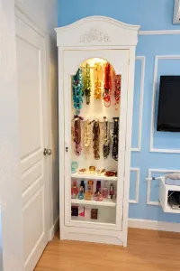 ตู้โชว์สีขาวหน้าบานกระจกโค้งพร้อมไฟภายในและเครื่องประดับที่จัดแสดง